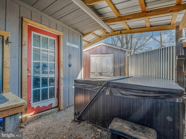 view of patio / terrace featuring a shed and a hot tub