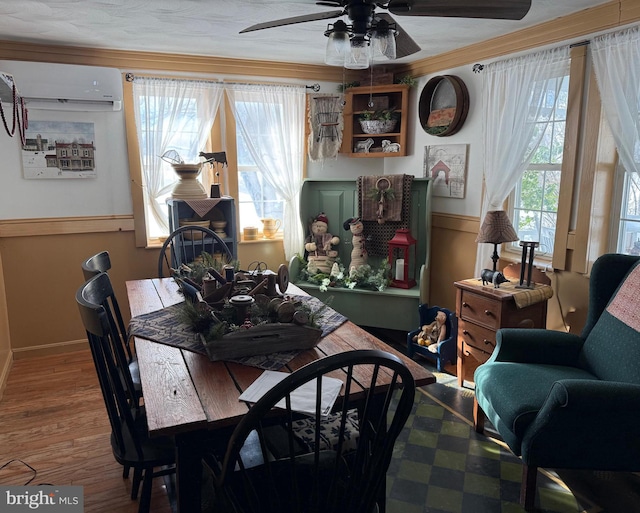 dining room featuring wood-type flooring, a wealth of natural light, a wall mounted air conditioner, and ornamental molding