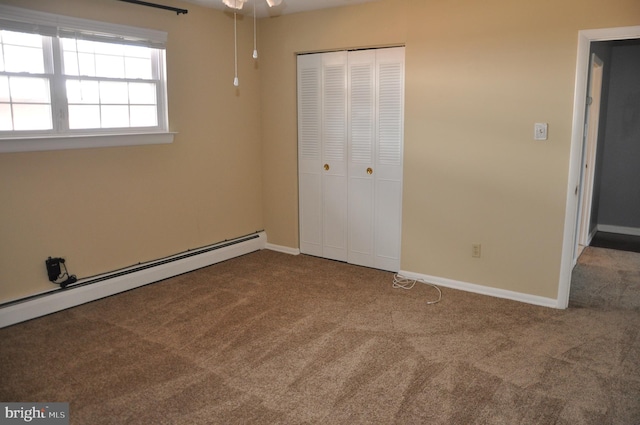 unfurnished bedroom with a closet, baseboard heating, and carpet floors