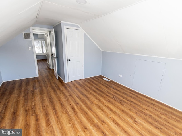 additional living space with dark wood-type flooring and vaulted ceiling