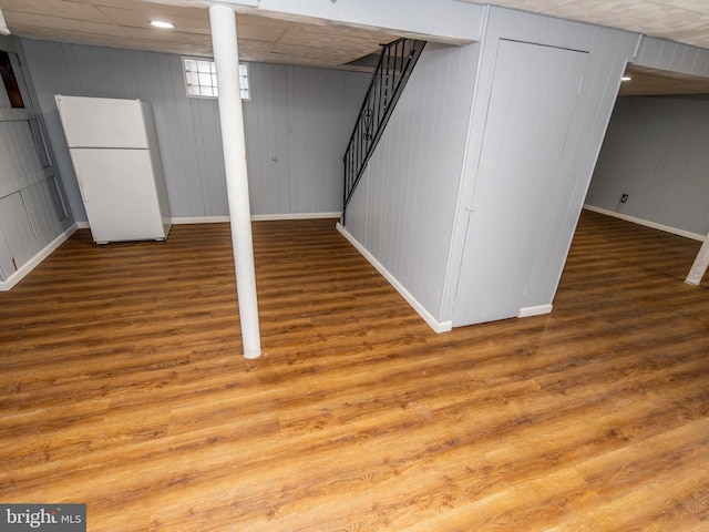 basement featuring white fridge and hardwood / wood-style floors