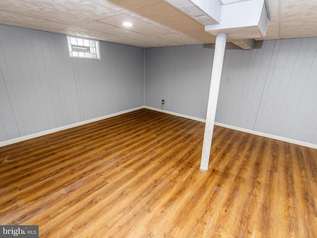 basement with wooden walls and light hardwood / wood-style flooring