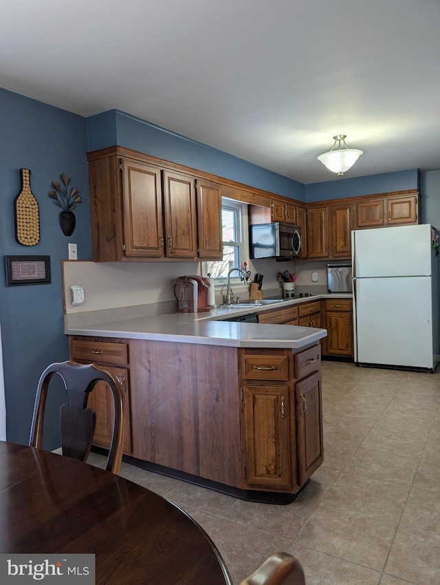 kitchen featuring white refrigerator, kitchen peninsula, and sink