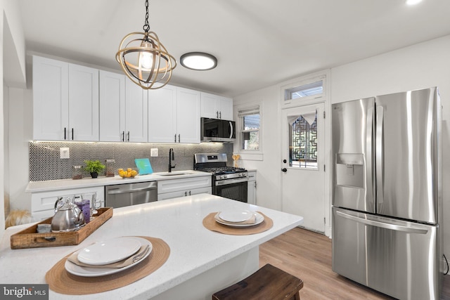 kitchen with white cabinetry, stainless steel appliances, sink, and backsplash