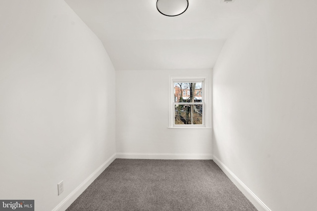 carpeted empty room featuring vaulted ceiling