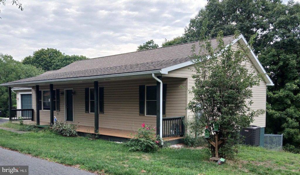 view of front of home featuring covered porch, central air condition unit, and a front lawn