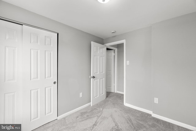 unfurnished bedroom featuring light carpet and a closet