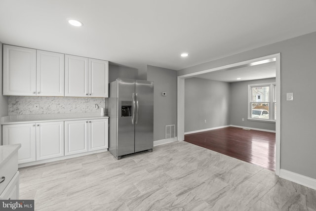 kitchen featuring white cabinetry, stainless steel fridge with ice dispenser, and backsplash