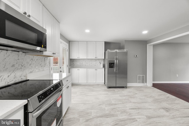 kitchen featuring white cabinetry, stainless steel appliances, and tasteful backsplash