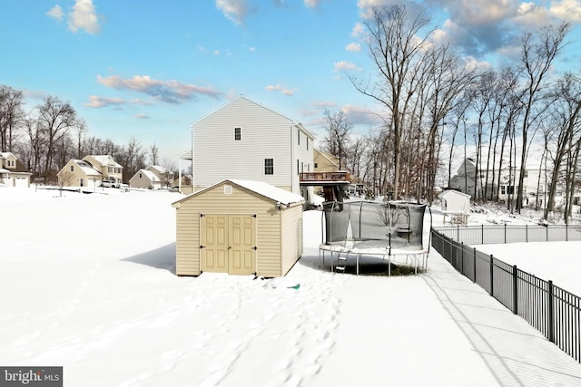 snow covered property with a storage shed and a trampoline