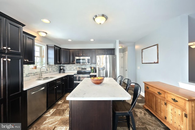 kitchen with appliances with stainless steel finishes, a kitchen island, decorative backsplash, sink, and a breakfast bar area