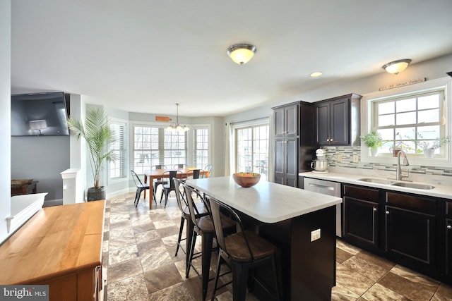 kitchen featuring pendant lighting, a kitchen island, tasteful backsplash, sink, and a breakfast bar area