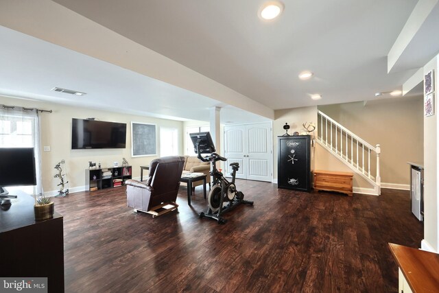 workout area featuring ornate columns and dark wood-type flooring