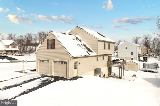 snow covered rear of property featuring a garage