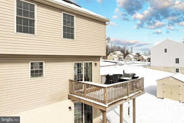 snow covered deck featuring a storage shed and grilling area