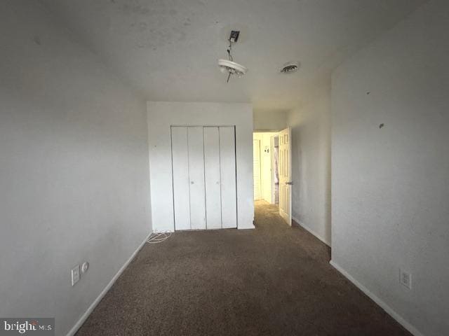 unfurnished bedroom featuring a closet and dark colored carpet