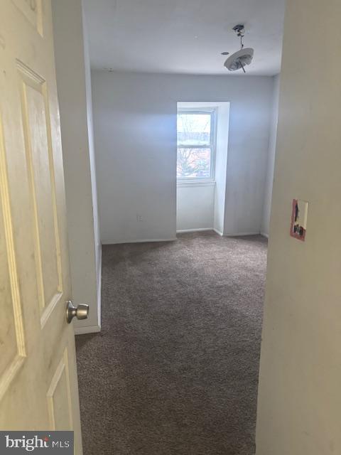 spare room with dark colored carpet