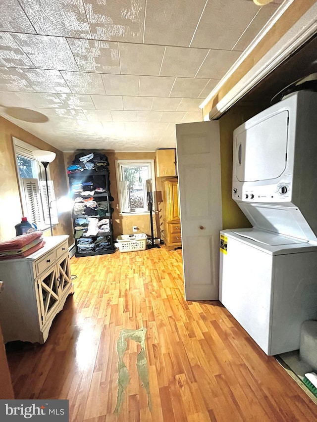 laundry area with stacked washer and clothes dryer and light wood-type flooring