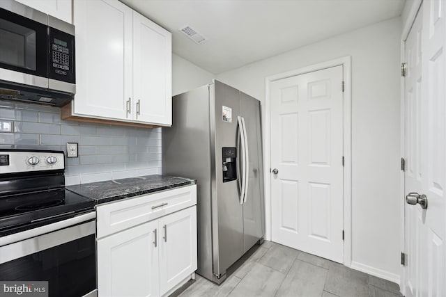 kitchen with tasteful backsplash, white cabinetry, appliances with stainless steel finishes, and dark stone countertops