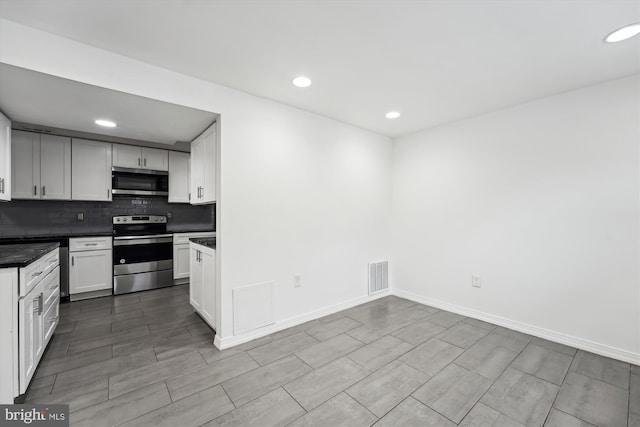 kitchen featuring stainless steel appliances, white cabinetry, and backsplash