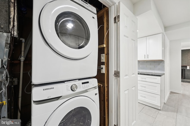 clothes washing area with stacked washer / drying machine and light tile patterned floors