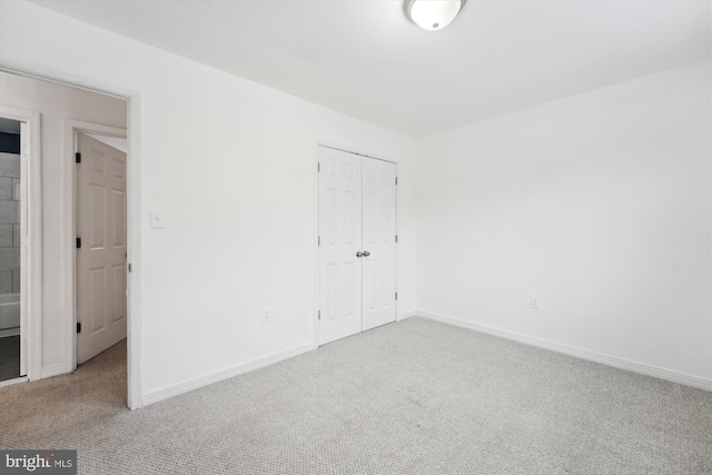 unfurnished bedroom with light colored carpet and a closet