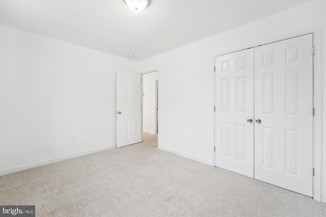 unfurnished bedroom featuring light colored carpet and a closet