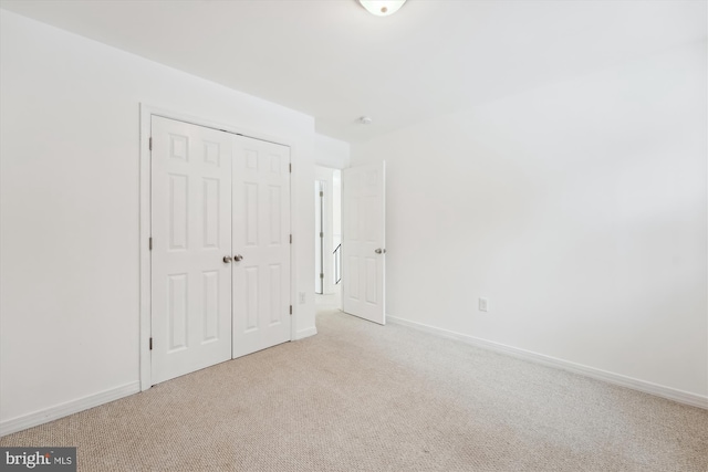 unfurnished bedroom with light colored carpet and a closet