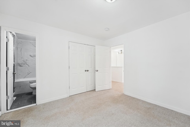 unfurnished bedroom with light colored carpet, ensuite bath, and a closet