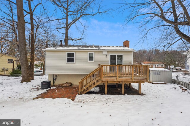 snow covered house featuring central AC unit and a deck