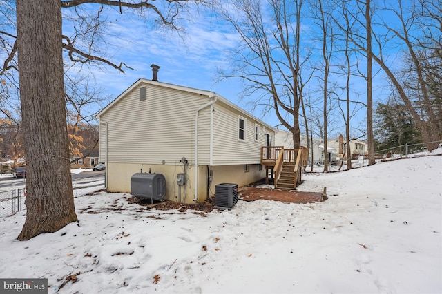 view of snowy exterior with cooling unit and a deck