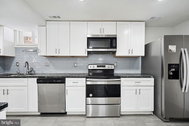 kitchen with stainless steel appliances, white cabinets, and dark stone counters