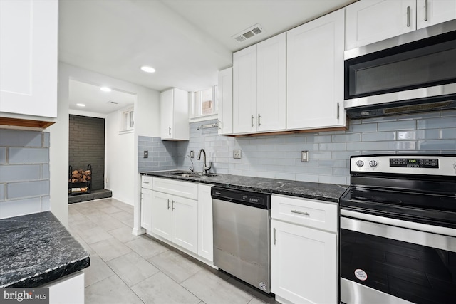 kitchen featuring appliances with stainless steel finishes, sink, dark stone counters, and white cabinets