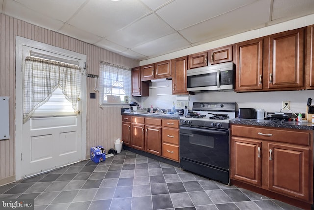 kitchen with gas range, wooden walls, and a drop ceiling