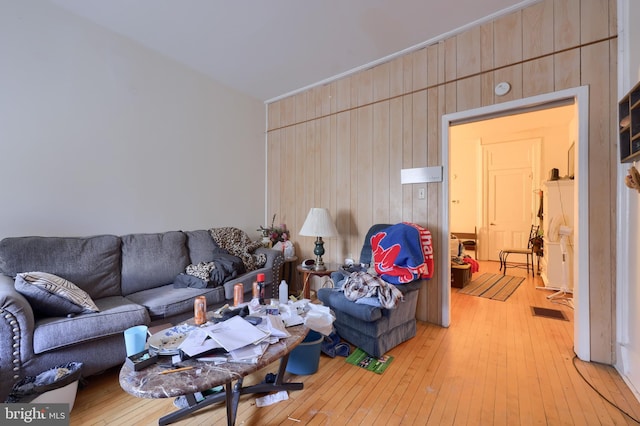 living room with wooden walls and light hardwood / wood-style flooring