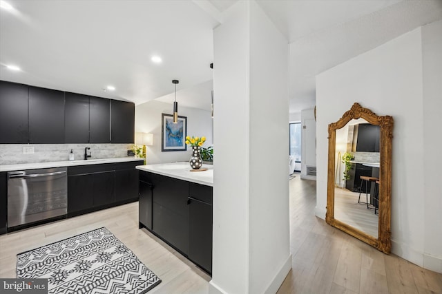 kitchen featuring tasteful backsplash, light hardwood / wood-style floors, stainless steel dishwasher, sink, and hanging light fixtures