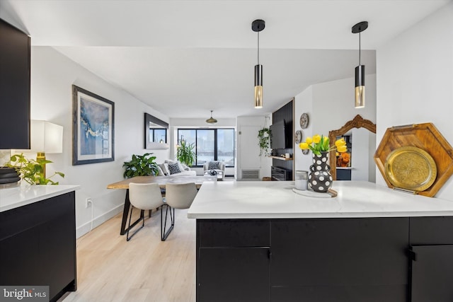 kitchen with light hardwood / wood-style floors, hanging light fixtures, and kitchen peninsula