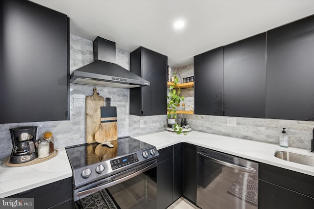 kitchen featuring wall chimney exhaust hood, stainless steel appliances, tasteful backsplash, sink, and light stone counters