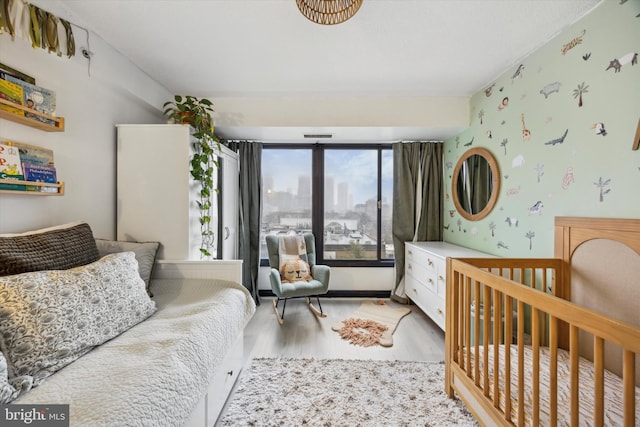 bedroom with light wood-type flooring and a nursery area