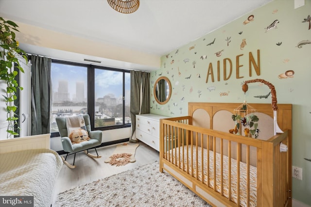 bedroom with light hardwood / wood-style flooring and a crib