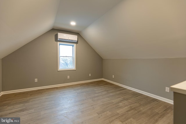 bonus room with wood-type flooring, vaulted ceiling, and a wall unit AC