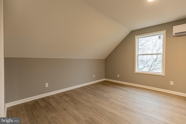 bonus room featuring a wall unit AC, vaulted ceiling, and light hardwood / wood-style flooring