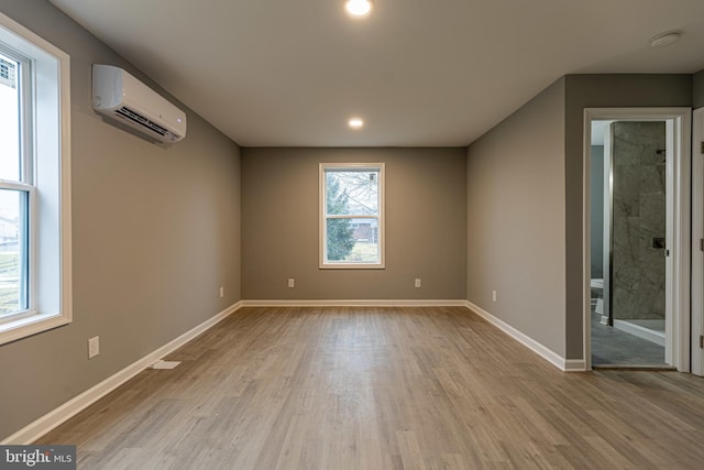 unfurnished room featuring an AC wall unit and light wood-type flooring