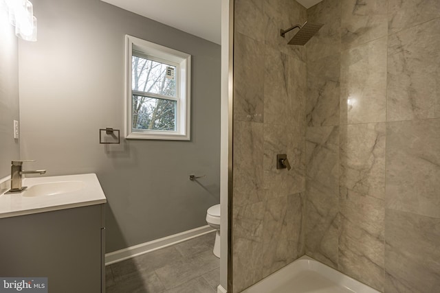 bathroom featuring vanity, tiled shower, and toilet