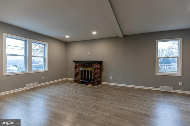 unfurnished living room with dark wood-type flooring, a fireplace, and beamed ceiling