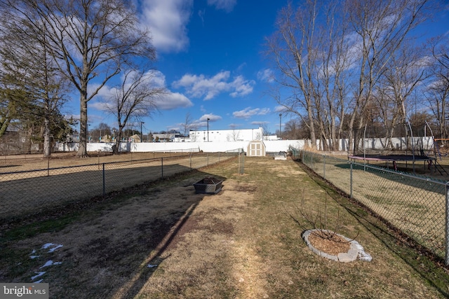 view of yard with a trampoline and a storage shed