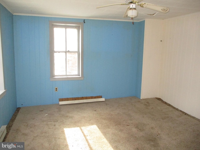 unfurnished room with ceiling fan, carpet, wooden walls, crown molding, and baseboard heating