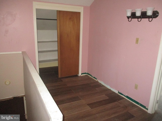 hallway with baseboards, dark wood-style flooring, and an upstairs landing