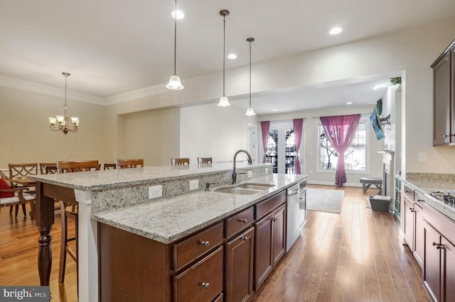 kitchen with pendant lighting, dishwasher, an island with sink, sink, and a breakfast bar