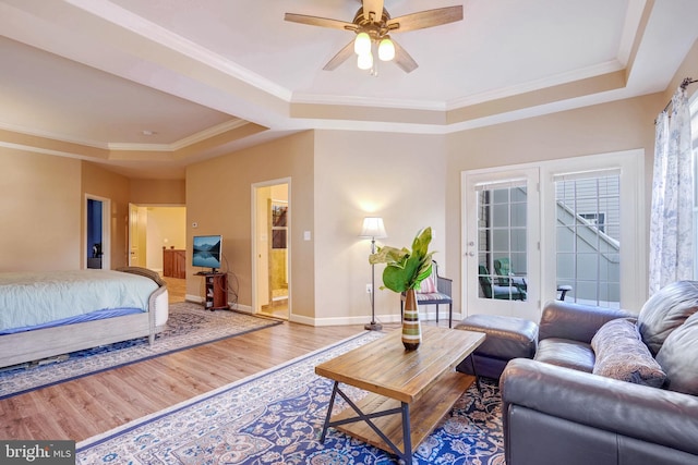 living room featuring a raised ceiling, wood-type flooring, crown molding, and ceiling fan